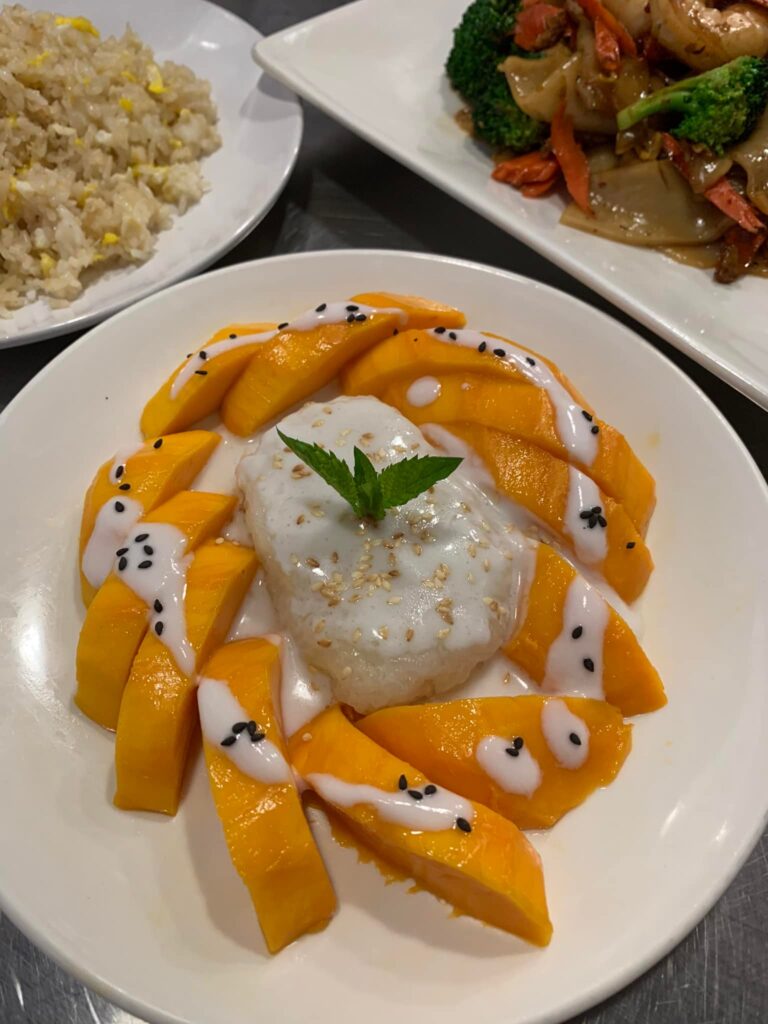 Thai mango sticky rice dessert with coconut cream and sesame seeds