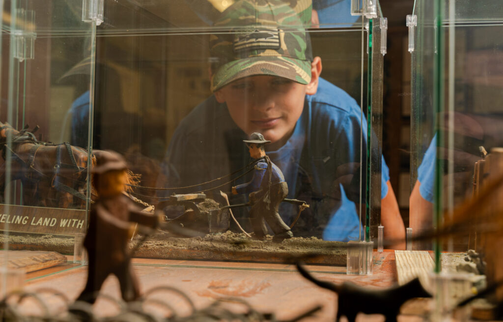 Boy in camo cap examining pioneer diorama at museum