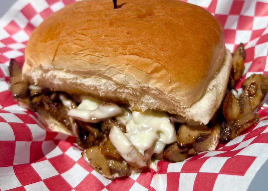 Cheesy mushroom sandwich on brioche bun with red checkered paper