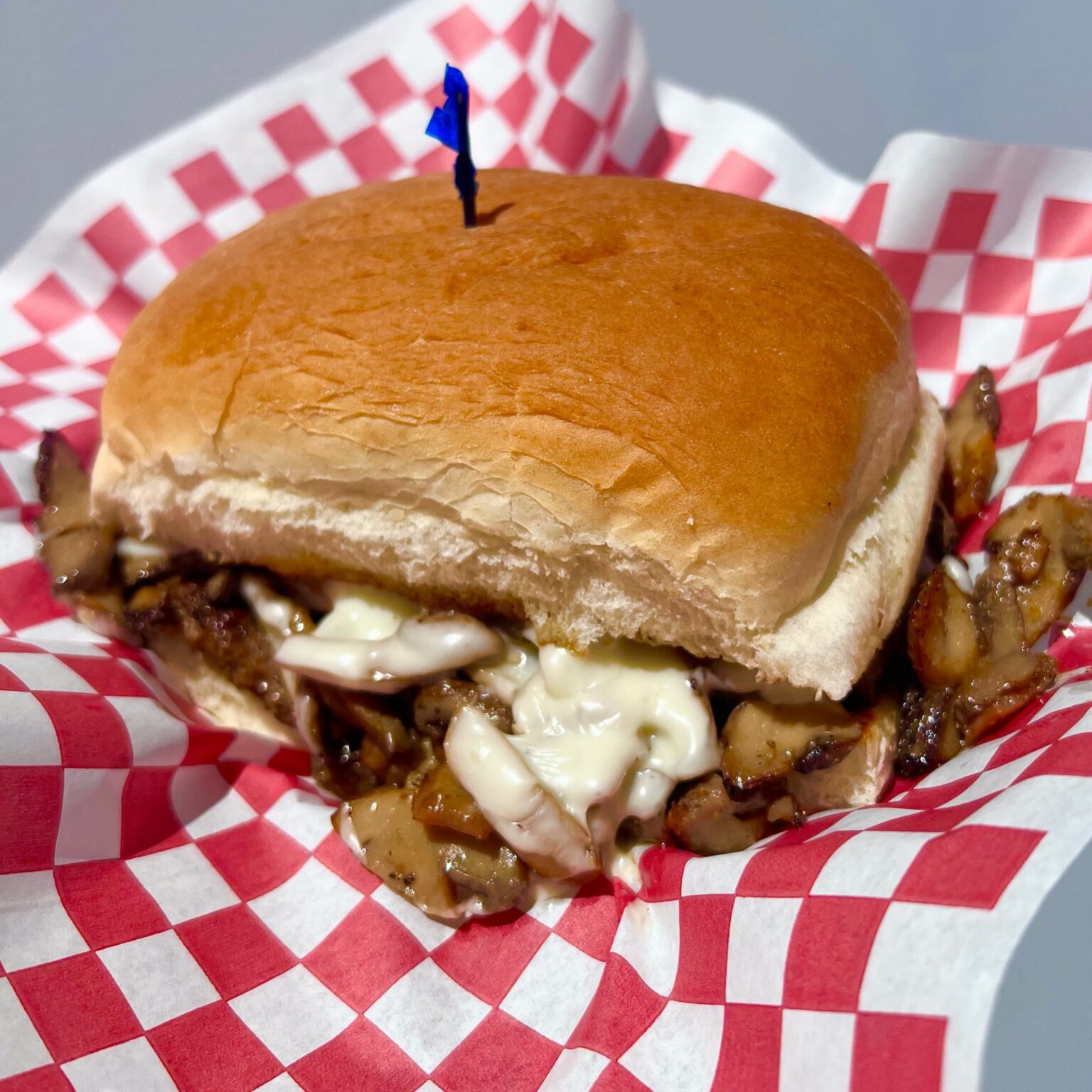 Mushroom Swiss burger overflowing with toppings on checkered paper