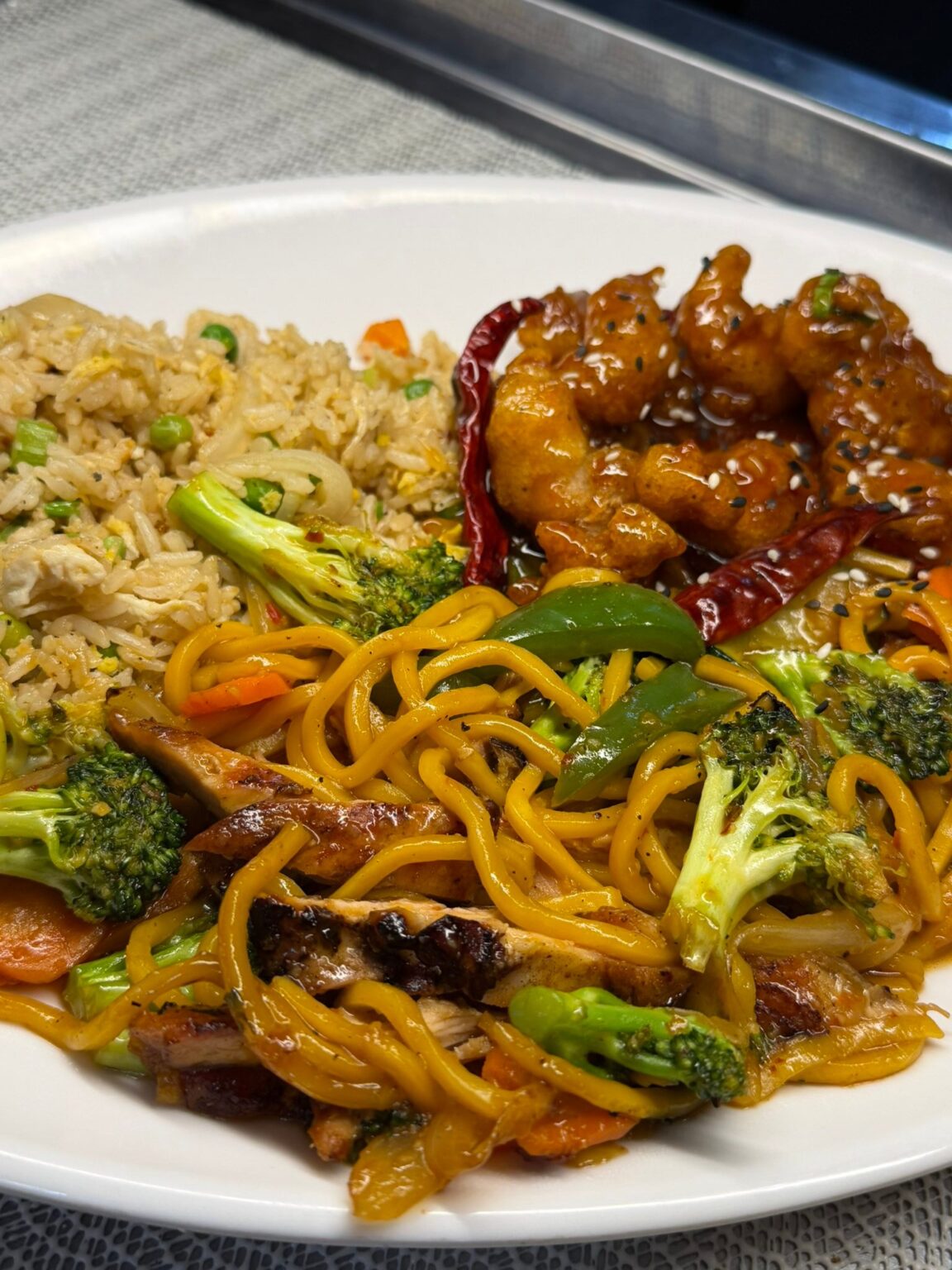 Chinese takeout plate with fried rice, noodles, and chicken